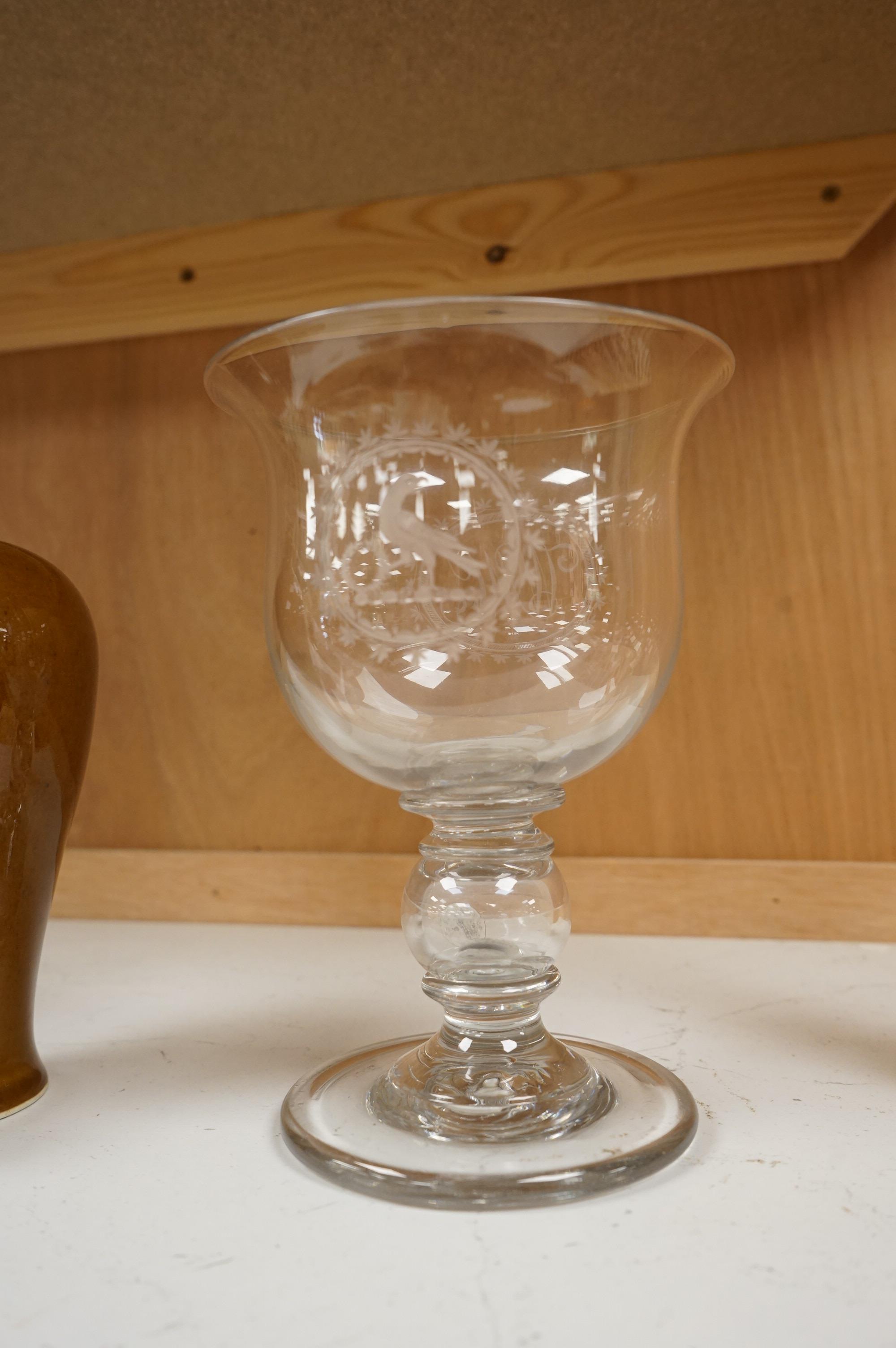 A large George III glass goblet, with inset coins to the hollow ball knopped stem, engraved with a parrot and the initials WMC, 20cm high